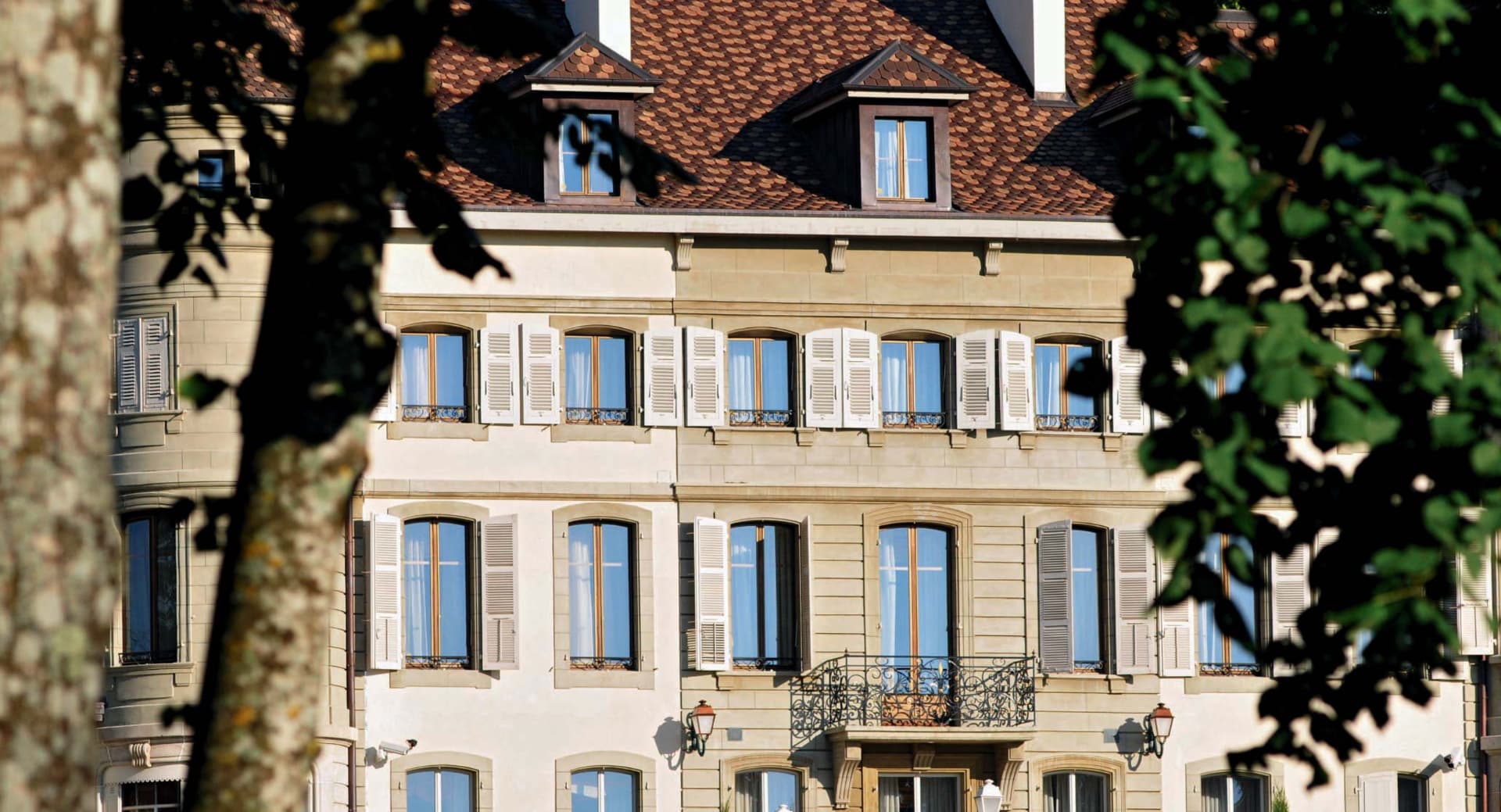 Façade d'immeuble genevois, pierre claire et volets blancs, symbole de l'ancrage d'Estate Advisory